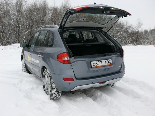 Рено Колеос на фоне зимнего леса с открытым багажником